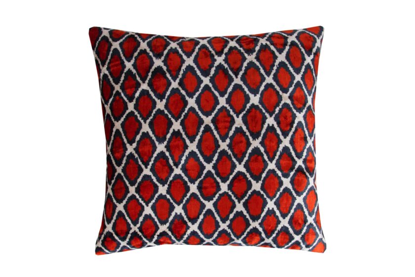 "Close-up view of a luxurious silk cushion cover in deep velvet red, showcasing an intricate Ikat pattern in shimmering gold threads. The soft, tactile texture of the silk velvet is highlighted, inviting touch and admiration. This elegant decorative accent adds sophistication and opulence to any room, whether placed on a sofa, chair, or bed. Handcrafted with care and attention to detail, it embodies the rich textile traditions of Uzbekistan, making it a timeless statement piece for discerning decor enthusiasts."